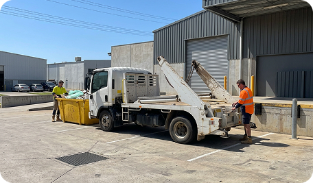Skip bin being collected from a commercial business in Curtin, showing professional waste removal service transporting a full bin for disposal